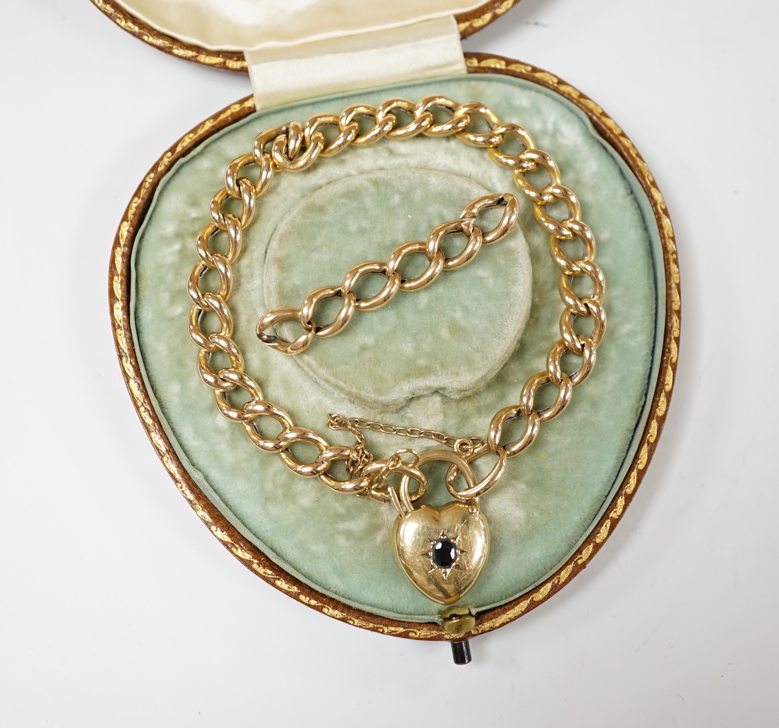 An Edwardian 15ct curblink bracelet, with sapphire set heart shaped padlock clasp, 18cm, with spare links, gross weight 13.6 grams.